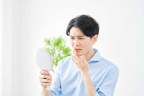 鏡をみる男性の画像