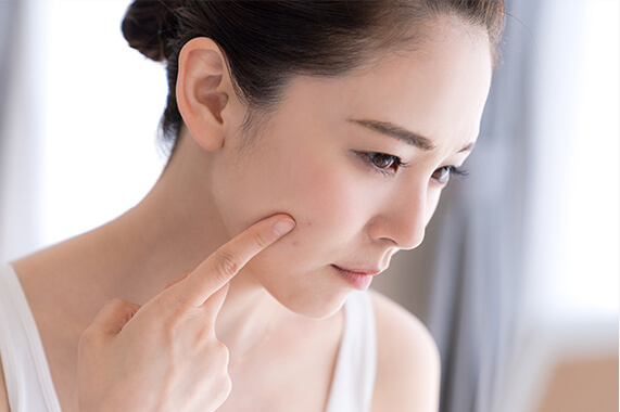 肌を指さす女性の画像