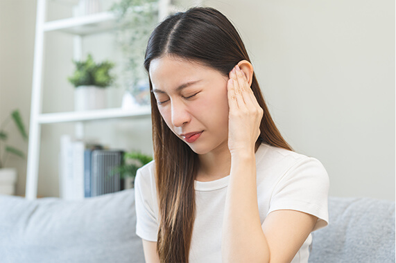 耳を抑える女性の画像